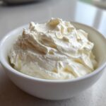 Close-up of thick, creamy horseradish sauce swirled high in a small white bowl.