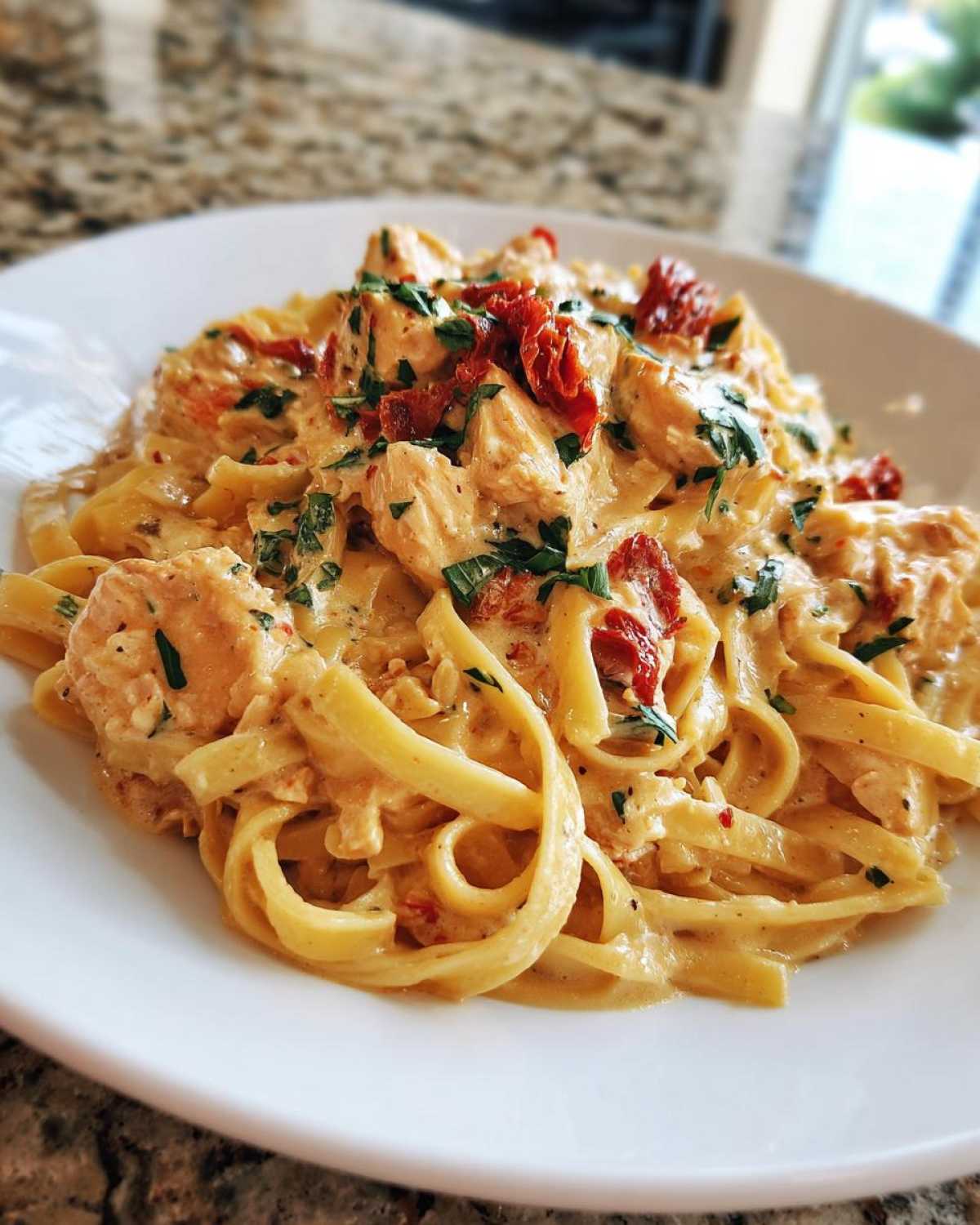Close-up of creamy Marry Me Chicken Pasta featuring fettuccine, chicken pieces, and sun-dried tomatoes.