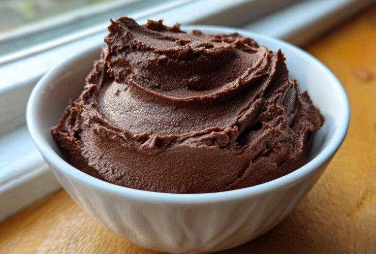 A close-up of thick, dark brown, whipped chocolate dip served in a small white bowl.