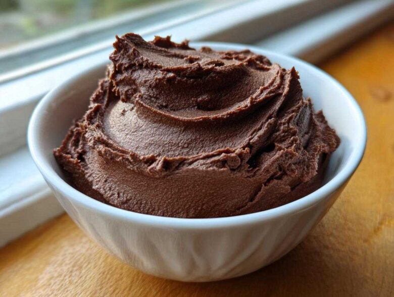 A close-up of thick, dark brown, whipped chocolate dip served in a small white bowl.