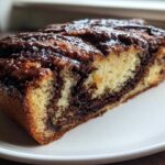 Close-up of a moist slice of chocolate babka showing rich chocolate swirls and a glossy topping.