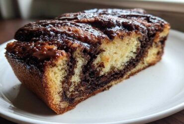 Close-up of a moist slice of chocolate babka showing rich chocolate swirls and a glossy topping.