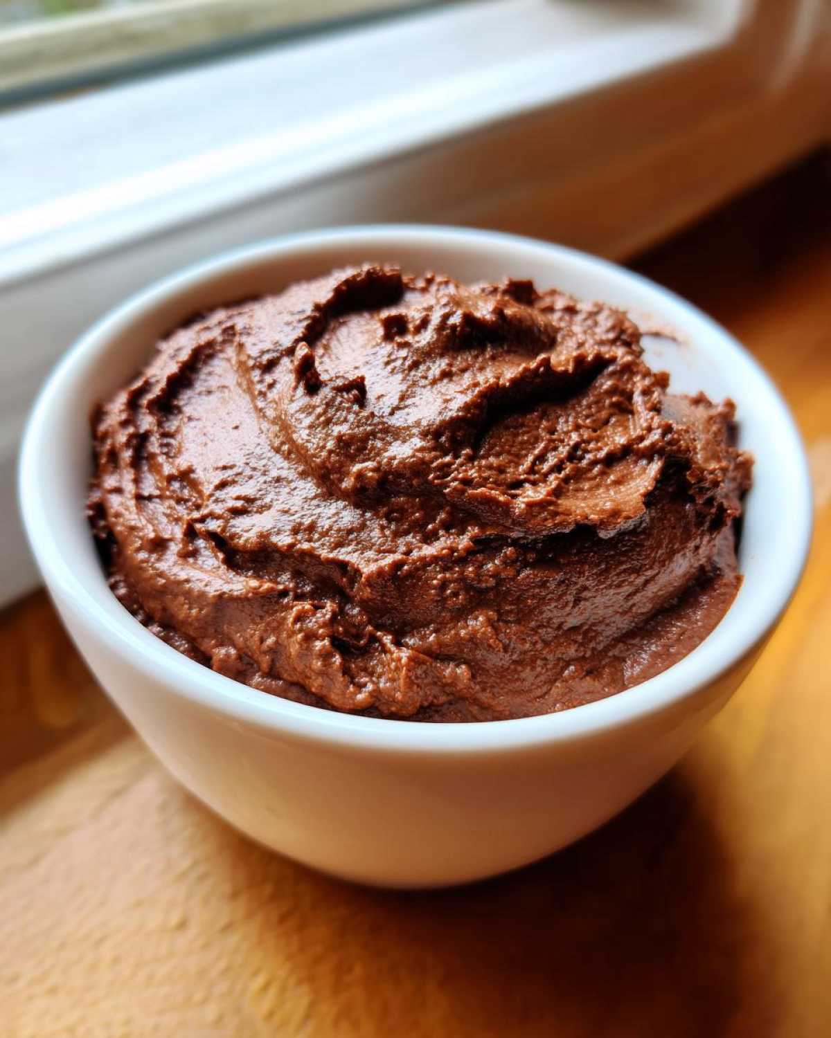 Close-up of thick, rich chocolate dip swirled in a small white bowl, ready for dipping.