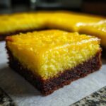 Close-up of a fudgy Lemon Brownies square showing a dark chocolate base and a thick, bright yellow lemon layer with glaze.