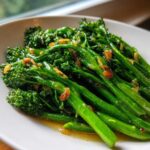 Close-up of bright green, perfectly cooked broccolini tossed in garlic and lemon sauce.