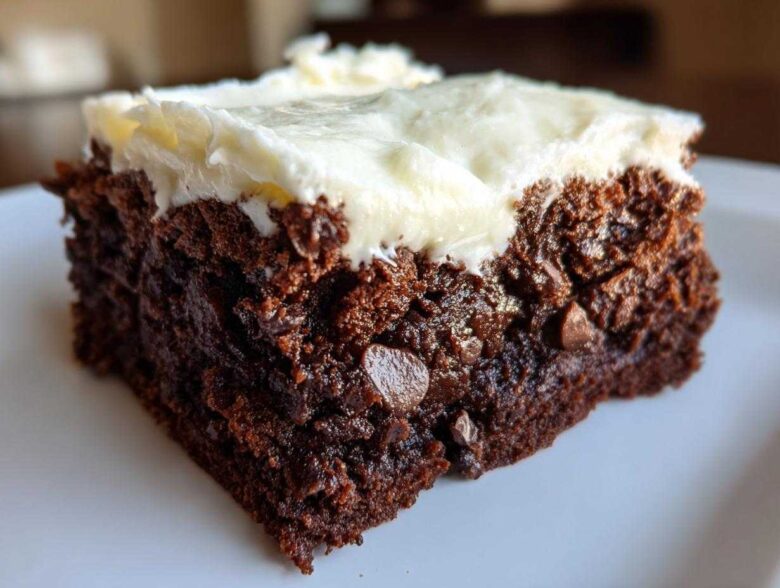 Close-up of a rich, dark slice of gingerbread brownies topped with thick cream cheese frosting.