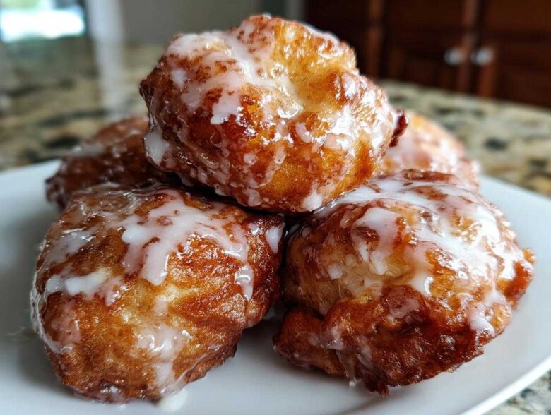 Close-up of several golden brown baked apple fritters generously drizzled with white glaze.