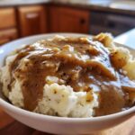 Close-up of creamy mashed potatoes generously topped with rich, savory homemade brown gravy.