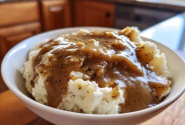 Close-up of creamy mashed potatoes generously topped with rich, savory homemade brown gravy.