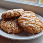 Close-up of three maple brown sugar cookies stacked on a white plate, drizzled with white icing and caramel.