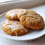 Close-up of three soft maple brown sugar cookies drizzled with a thick, glossy maple glaze.