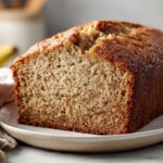 Close-up of a thick slice of moist best banana bread showing its tender crumb and golden-brown crust.