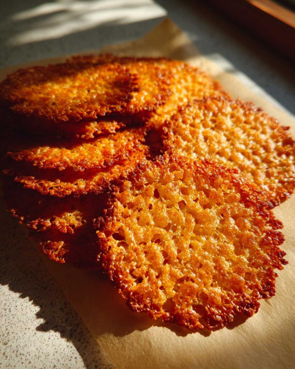 Close-up of several golden brown, delicate oatmeal lace cookies showing their signature lacy texture.