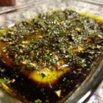 Close-up of olive oil bread dip ingredients, including olive oil, balsamic vinegar, garlic, and herbs, ready for mixing.
