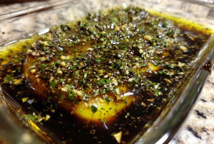 Close-up of olive oil bread dip ingredients, including olive oil, balsamic vinegar, garlic, and herbs, ready for mixing.
