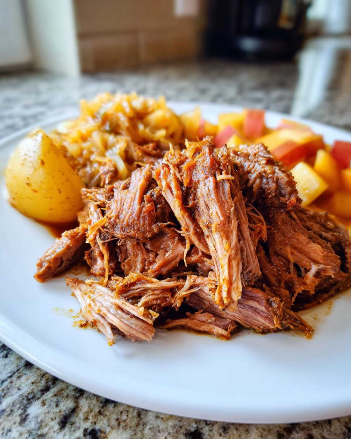 Close-up of shredded pork and sauerkraut served with a potato wedge and diced apples.