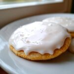 Close-up of a soft sugar cookie topped with thick, glossy white sugar cookie icing that hardens.