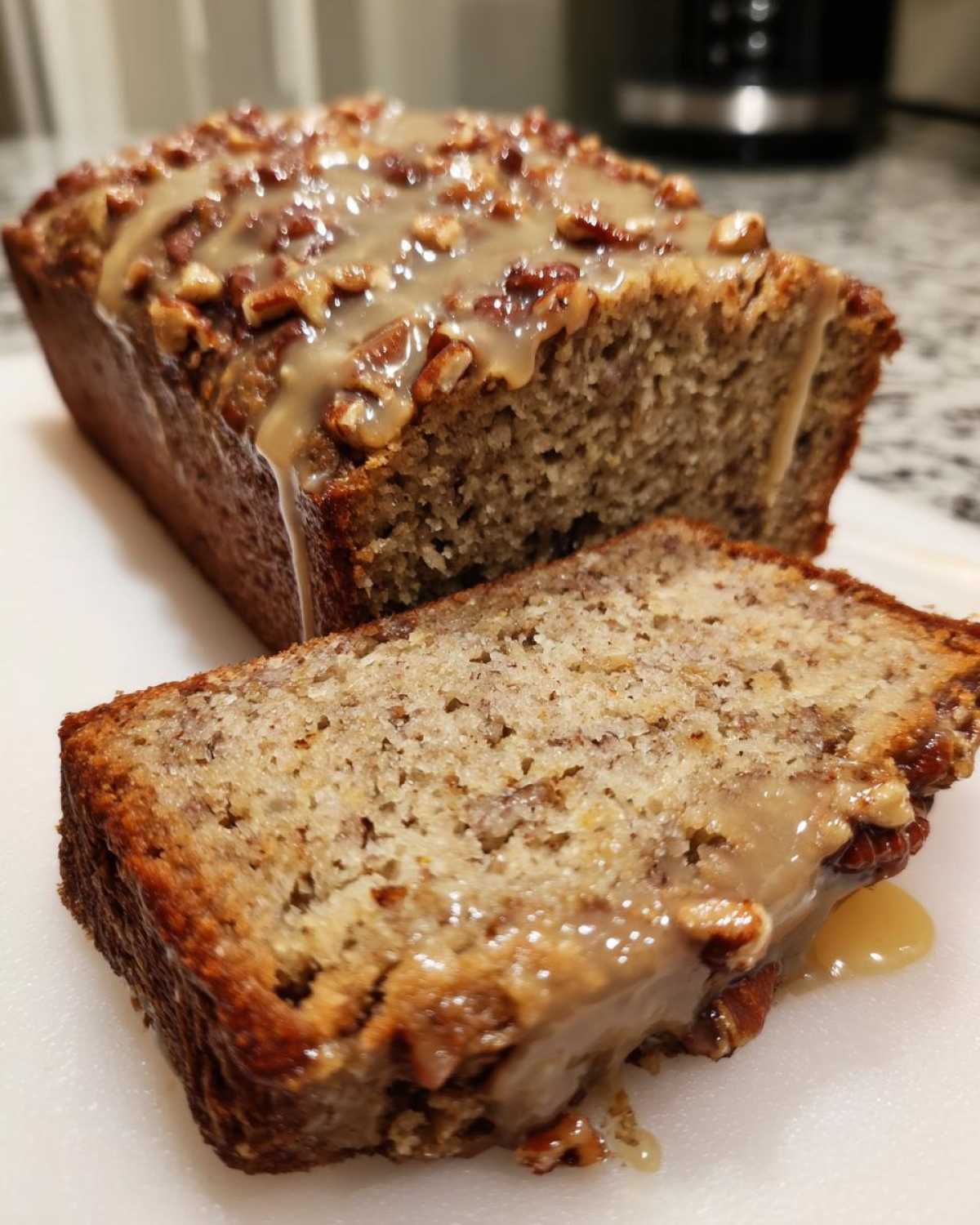 A slice of moist sweet alabama pecan bread topped with a thick caramel glaze and chopped pecans.