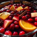 Close-up of vibrant holiday sangria floating with cranberries, orange slices, apple chunks, star anise, and cinnamon sticks.