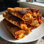 A stack of crispy Air Fryer Crispy Buffalo Chicken Taquitos showing shredded, saucy chicken filling.