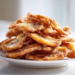 A close-up stack of Air Fryer Crispy Cinnamon Sugar Banana Chips piled high on a white plate.