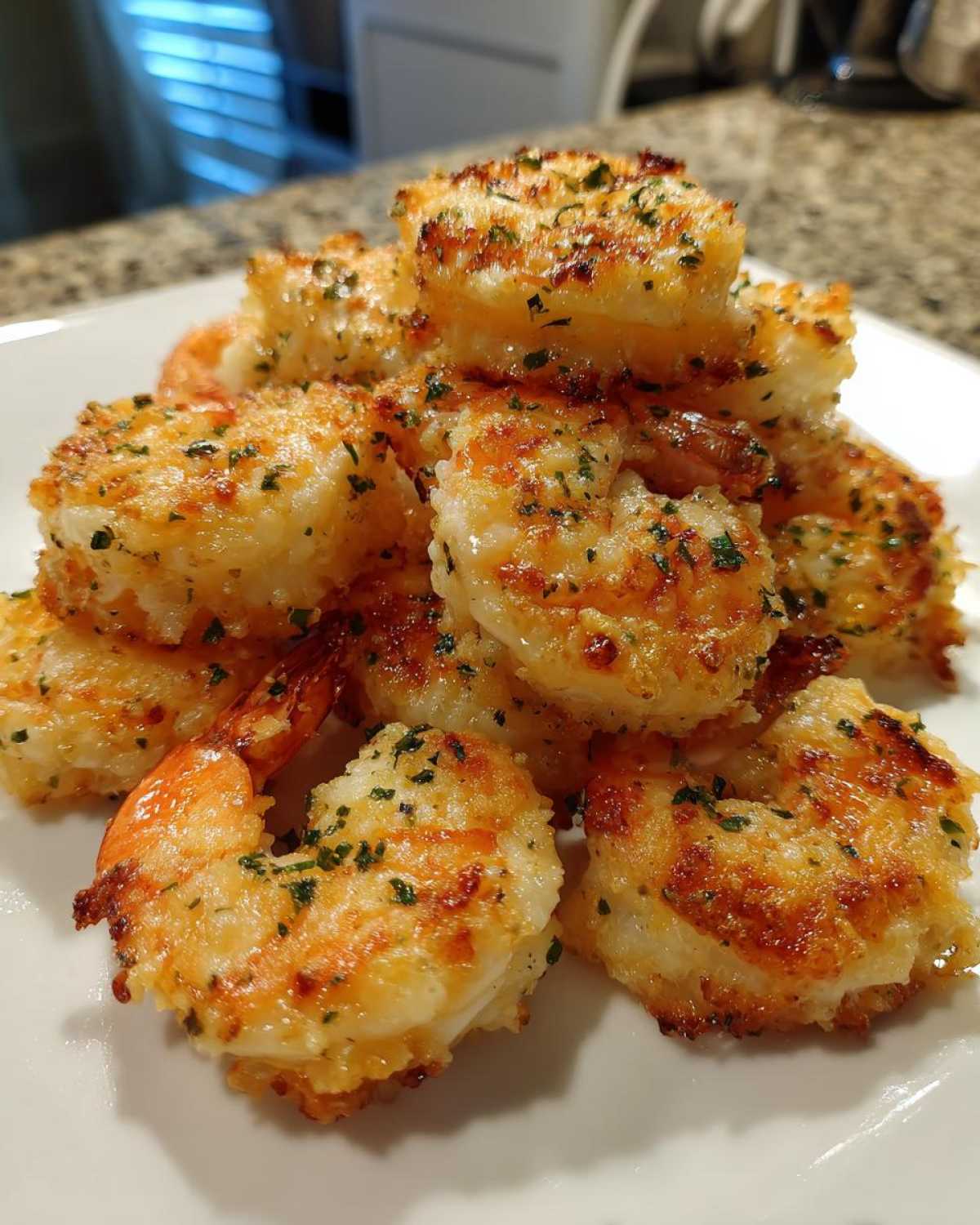 A pile of golden brown Air Fryer Crispy Garlic Parmesan Shrimp seasoned with parsley on a white plate.