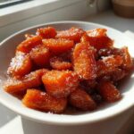 Close-up of glossy Air Fryer Maple Glazed Carrots sprinkled with sugar in a white bowl.