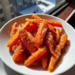 Close-up of bright orange Air Fryer Maple Glazed Carrots coated heavily in sparkling sugar crystals in a white bowl.