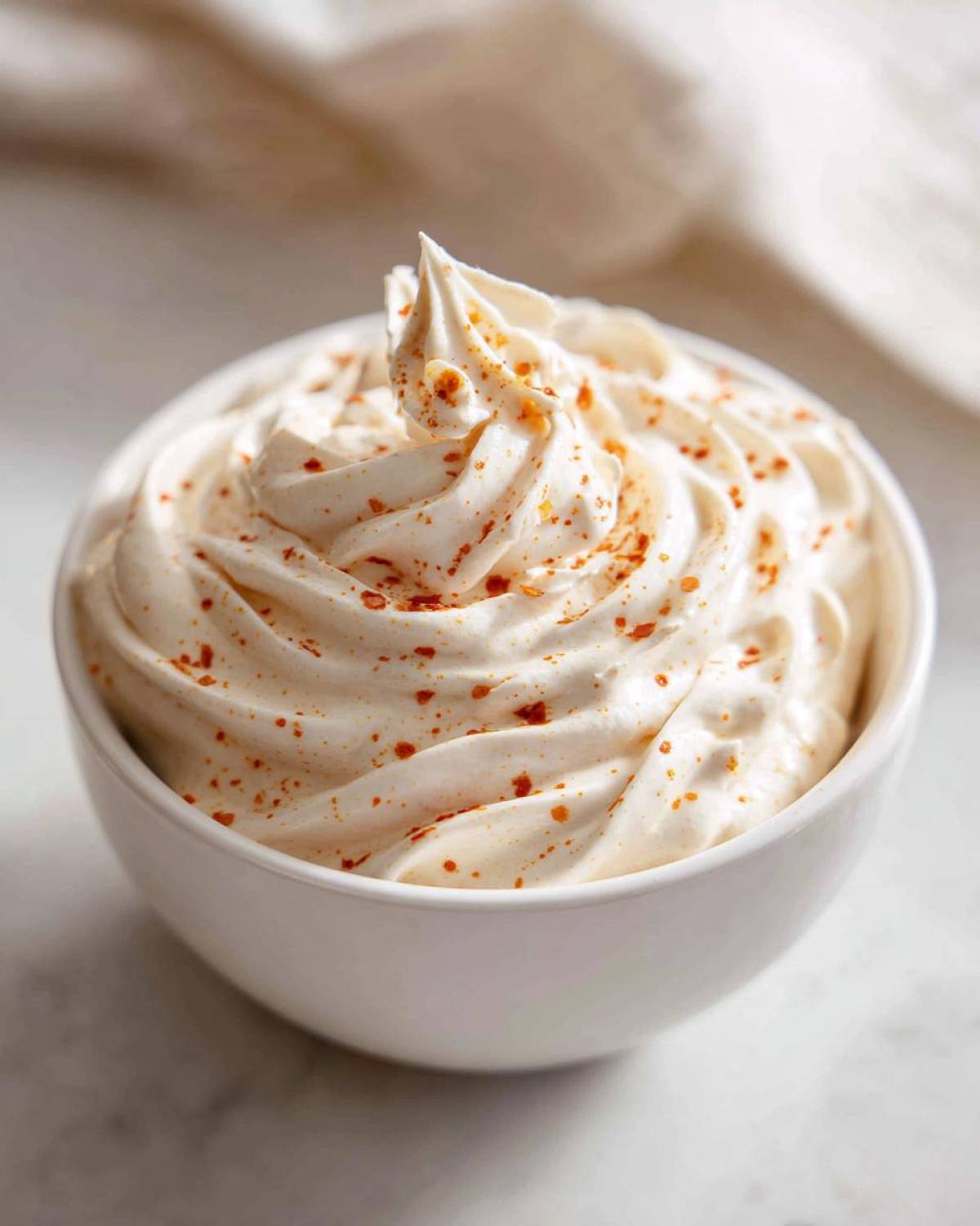 A white bowl filled with creamy, swirled Copycat Outback Bloomin' Onion Sauce, sprinkled with paprika.