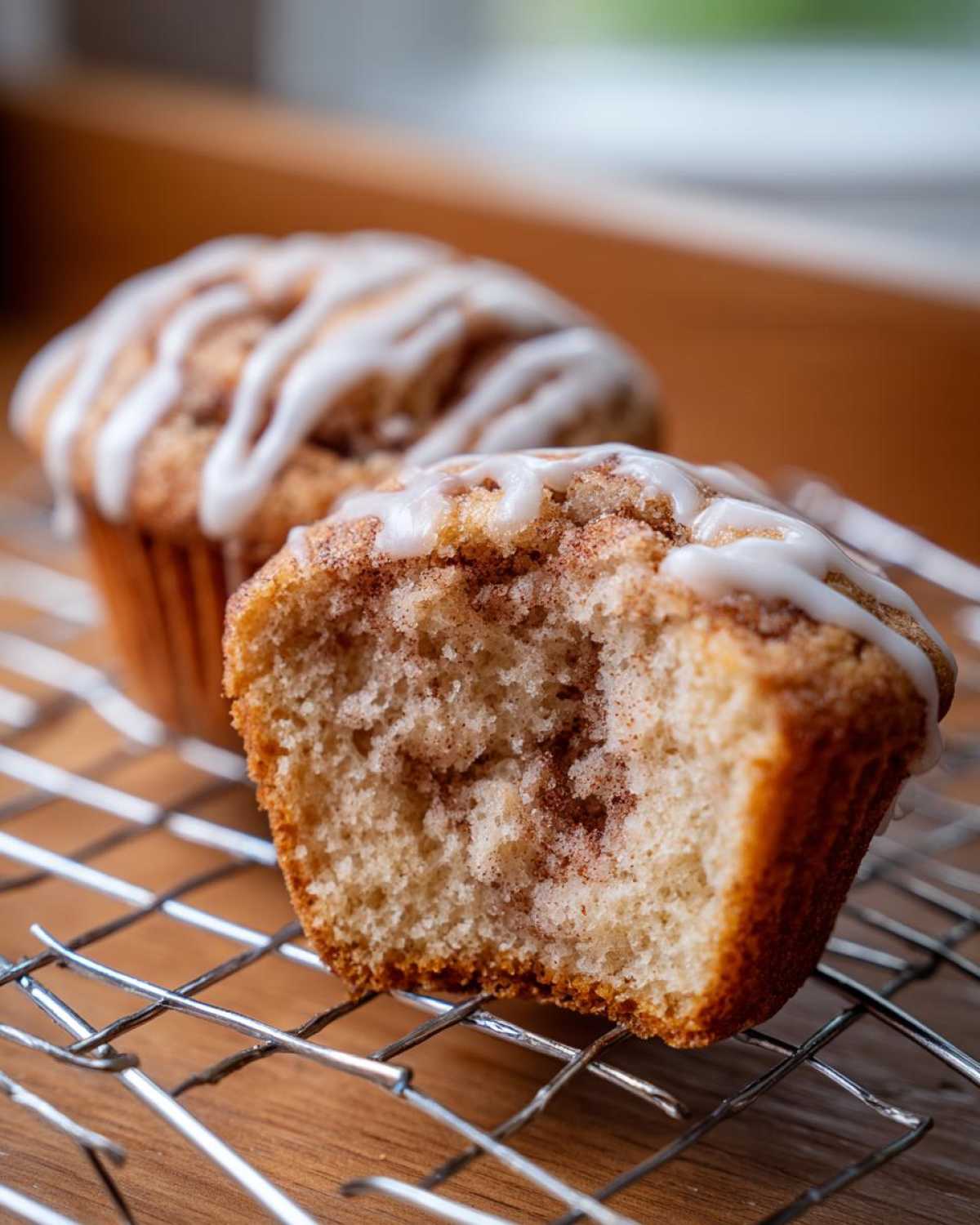 Close-up of a Gluten-Free Cinnamon Roll Muffin cut in half showing the swirl texture and icing.