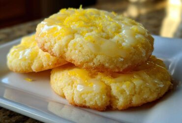 Three stacked Gluten-Free Lemon Sugar Cookies topped with a bright yellow glaze and fresh lemon zest.