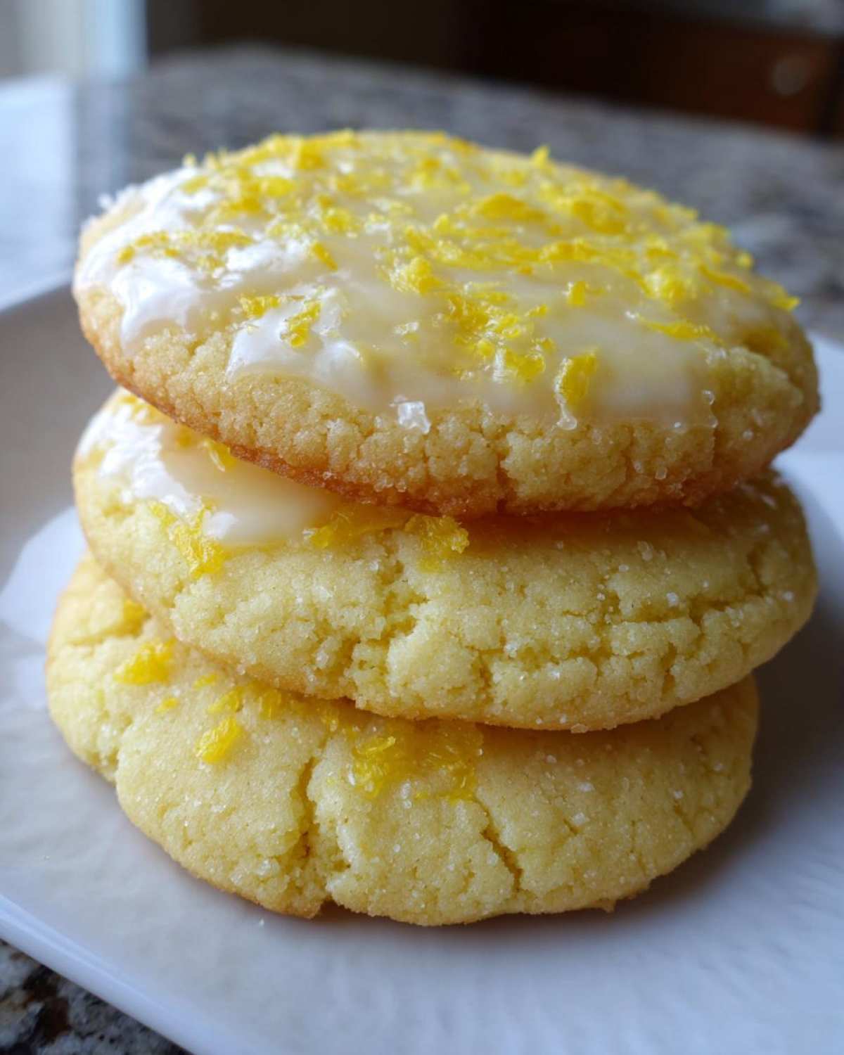Three stacked Gluten-Free Lemon Sugar Cookies topped with bright yellow zest and white glaze.