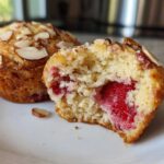 Close-up of a Gluten-Free Strawberry Almond Muffin cut in half showing a moist interior and whole strawberry filling.