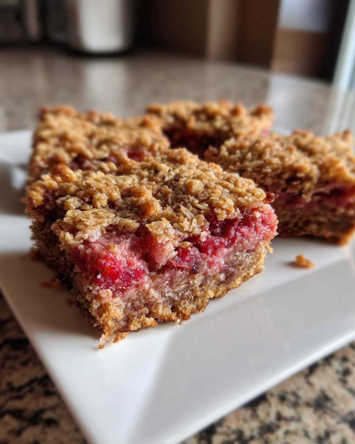 Close-up of a square slice of Gluten-Free Strawberry Rhubarb Bars showing the thick, crumbly oat topping and bright red fruit filling.