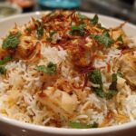 A close-up serving of flavorful Instant Pot Chicken Biryani topped with fried onions and fresh mint leaves.