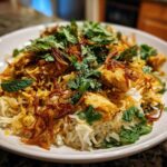 A close-up of a serving of Instant Pot Chicken Biryani, featuring saffron rice, chicken pieces, and topped with mint and fried onions.