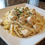 Close-up of Instant Pot Creamy Chicken Alfredo Pasta with chunks of chicken and parsley garnish.