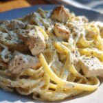 Close-up of creamy fettuccine pasta tossed with chunks of chicken, seasoned for Instant Pot Creamy Chicken Alfredo Pasta.