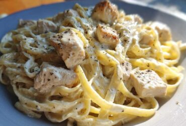 Close-up of creamy fettuccine pasta tossed with chunks of chicken, seasoned for Instant Pot Creamy Chicken Alfredo Pasta.