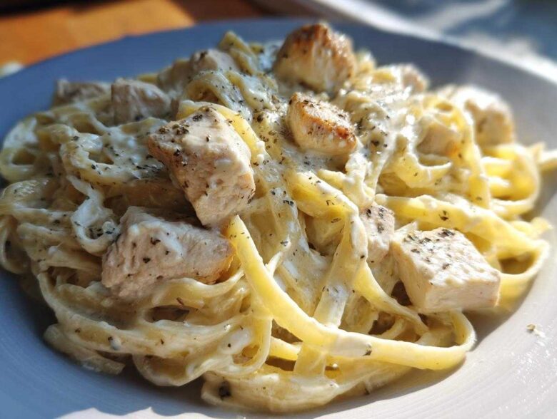 Close-up of creamy fettuccine pasta tossed with chunks of chicken, seasoned for Instant Pot Creamy Chicken Alfredo Pasta.