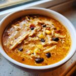 Close-up of a white bowl filled with rich, creamy Instant Pot Creamy Chicken Taco Soup featuring shredded chicken, black beans, and corn.