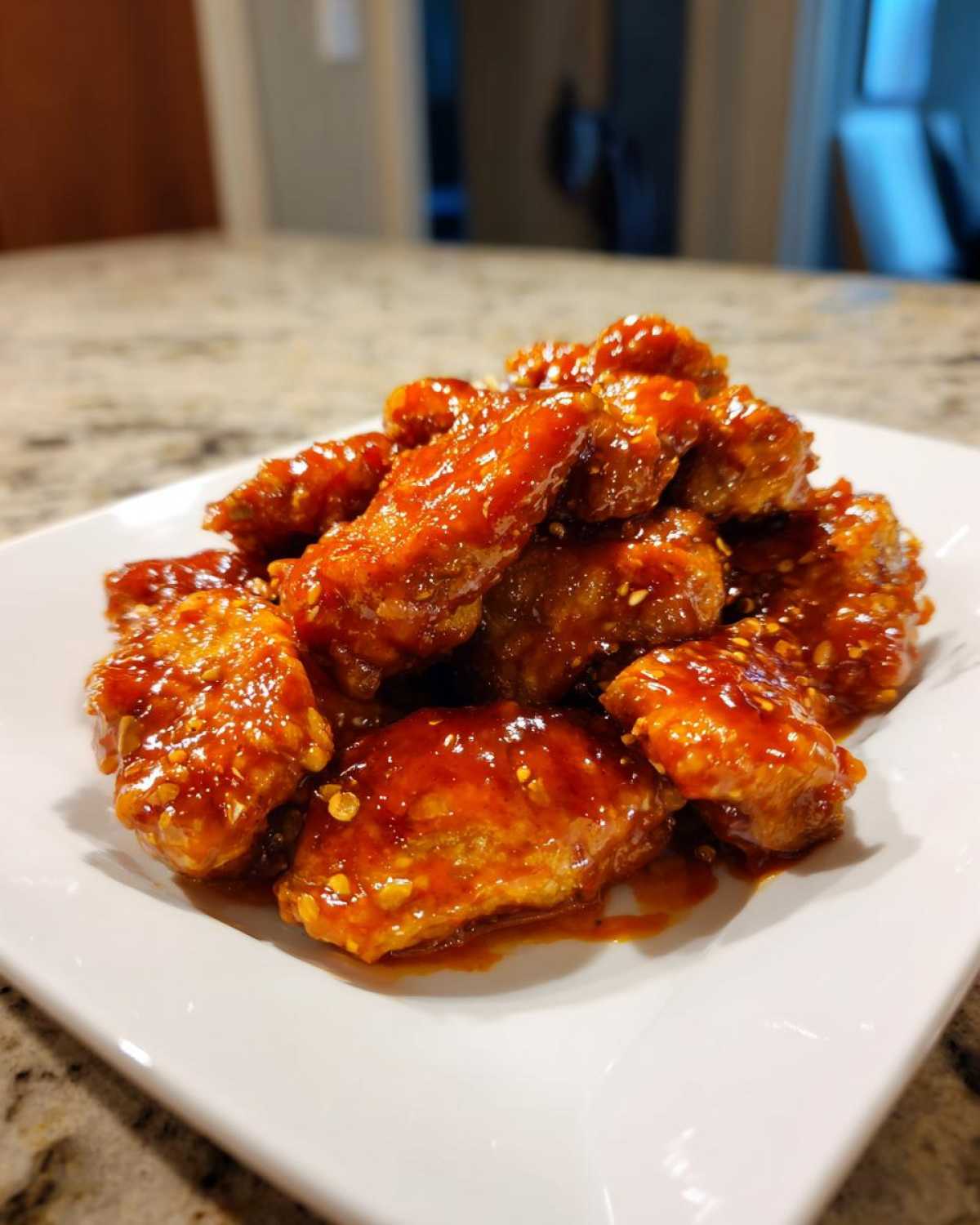 A pile of sticky, glazed chicken pieces coated in a vibrant red sauce, representing Instant Pot Honey Sriracha Chicken.