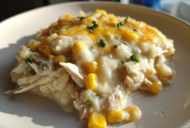 A close-up of a creamy serving of Instant Pot White Chicken Chili with Corn topped with melted cheddar cheese.