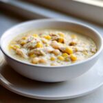 A close-up of a white bowl filled with creamy Instant Pot White Chicken Chili with Corn and white beans.