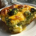 A close-up of a serving of Keto Cheesy Broccoli Casserole with a golden-brown top and melted cheddar cheese.