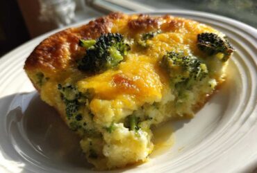 A close-up of a serving of Keto Cheesy Broccoli Casserole with a golden-brown top and melted cheddar cheese.