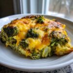 A close-up of a serving of Keto Cheesy Broccoli Casserole topped with bubbly, melted cheddar cheese.