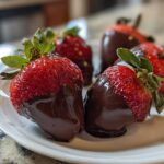 Close-up of fresh strawberries partially dipped in rich, dark chocolate, ready to enjoy as Keto Chocolate Covered Strawberries.