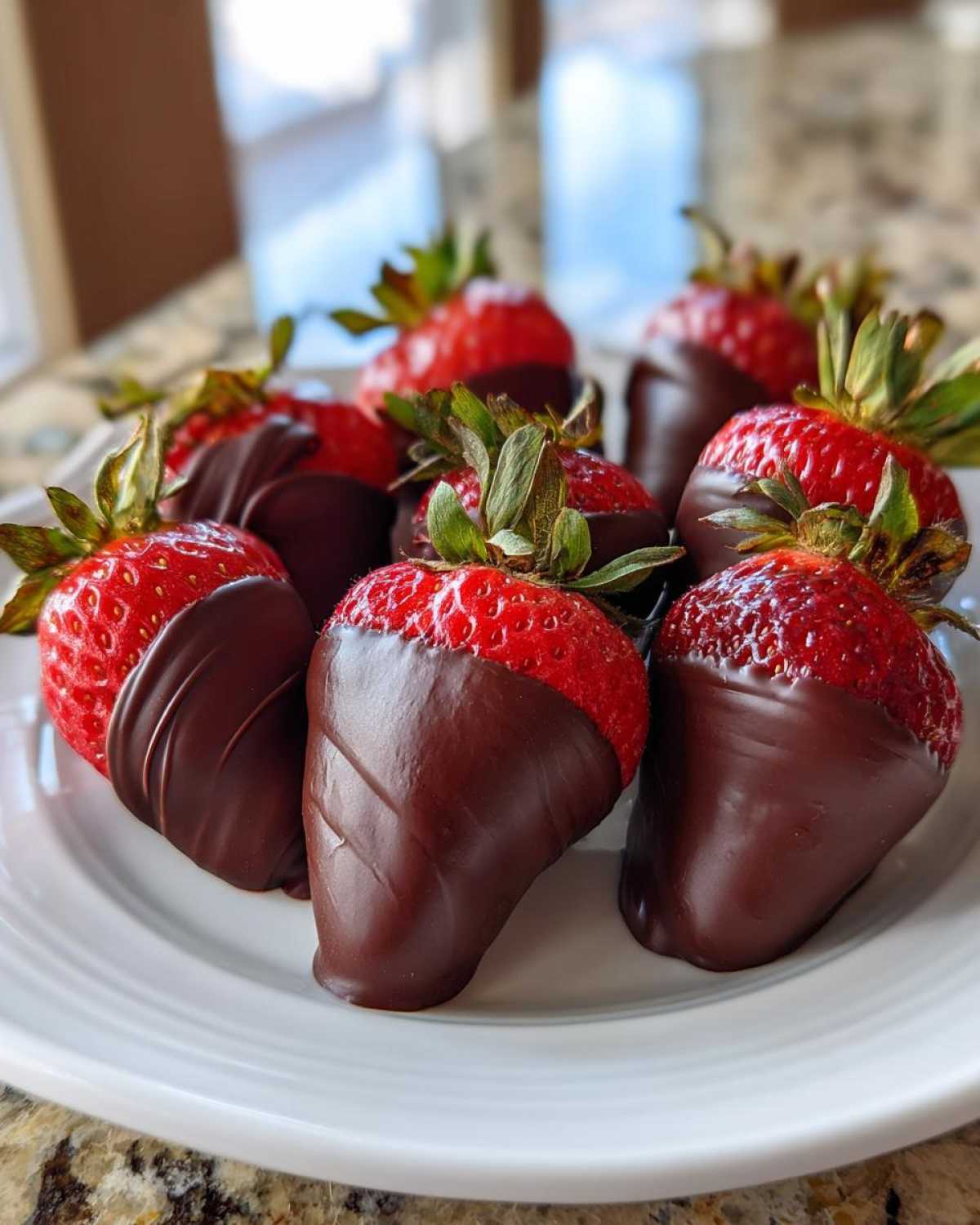A close-up of several fresh strawberries dipped in dark chocolate, ready to eat, showcasing perfect Keto Chocolate Covered Strawberries.