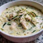 Close-up of a white bowl filled with Keto Creamy Chicken Zoodle Soup, featuring shredded chicken and zucchini noodles in a rich broth.